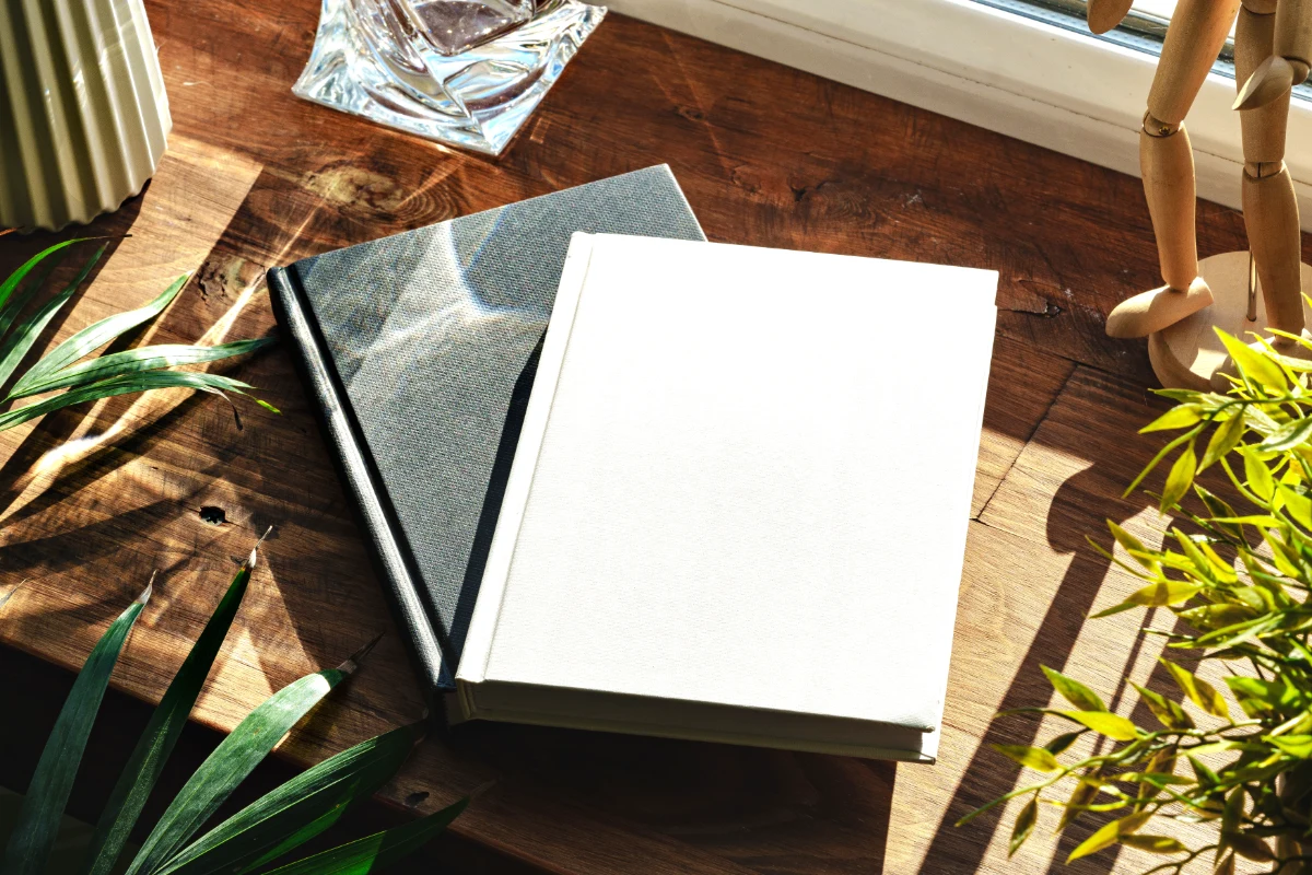 Two books on a wooden table surrounded by plants and work materials
